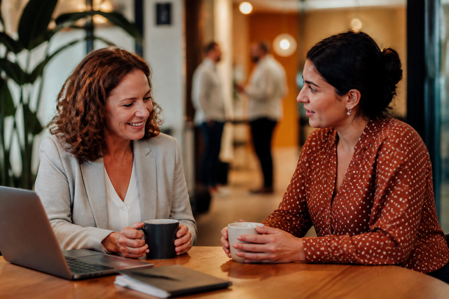 Two UK HR professionals sitting at a desk reviewing employee benefit options in a modern office.