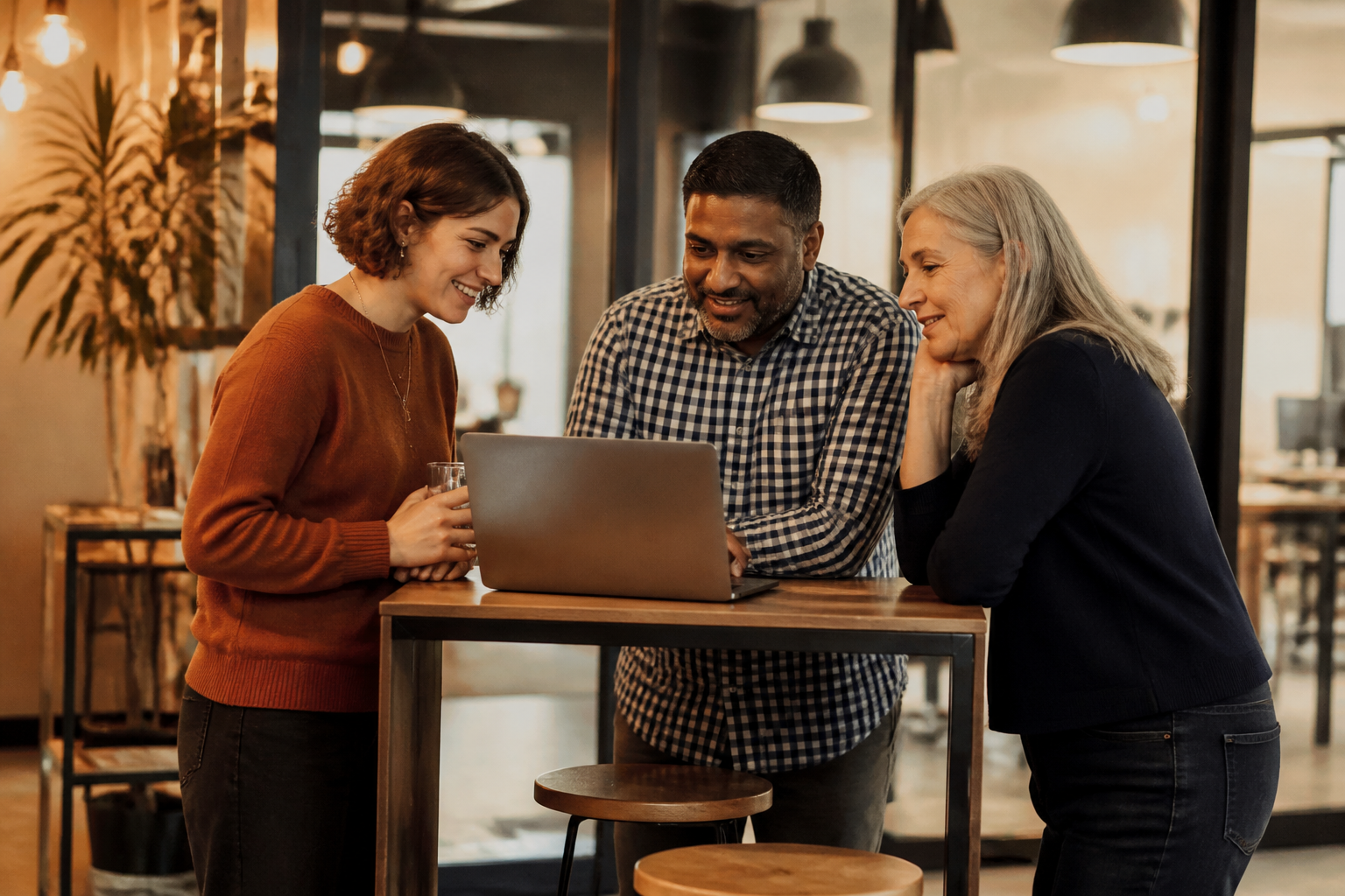 A small team of UK office workers discussing workplace initiatives around a laptop.