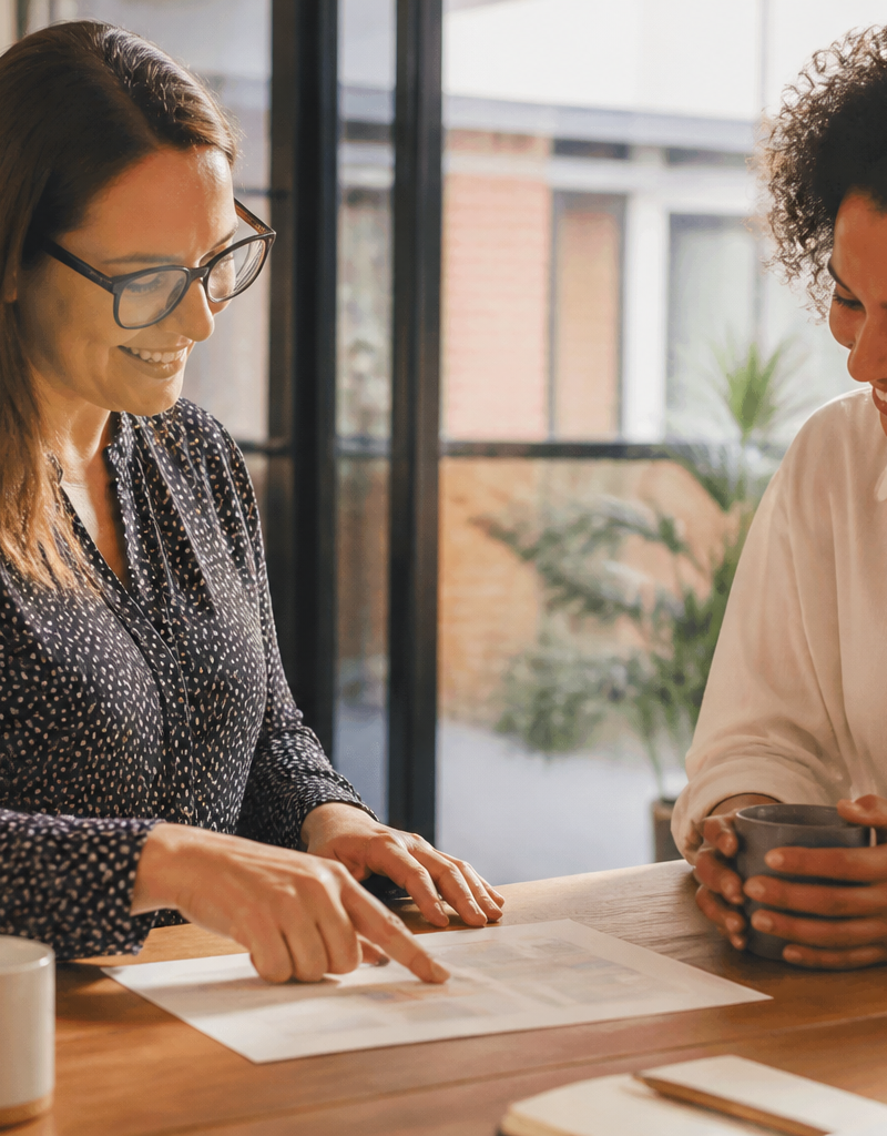 An HR manager and an employee discussing workplace benefits over coffee in a bright UK office