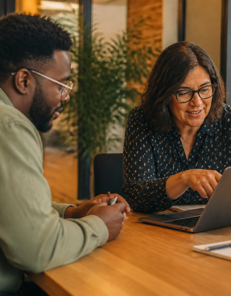 An HR director and employee discussing workplace benefits in a bright UK office.